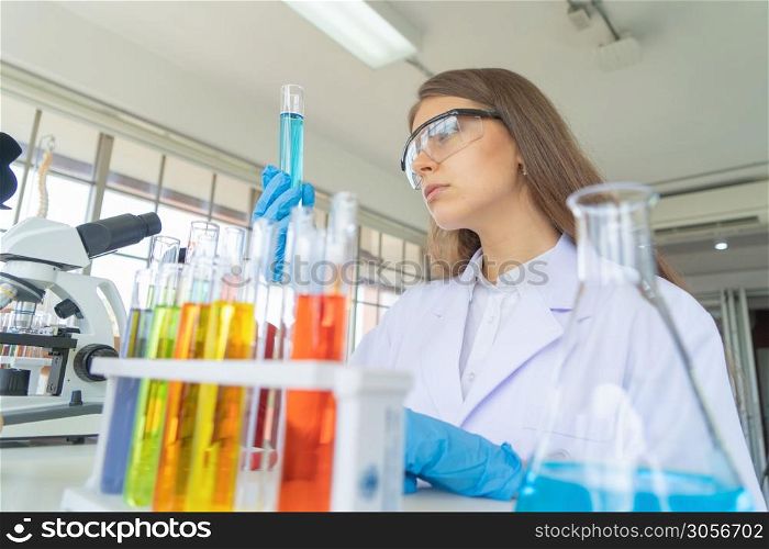 A western scientist woman working on test tube to analysis and develop vaccine of covid-19 virus in lab or laboratory in technology medical, chemistry, healthcare, research. Experimental science.