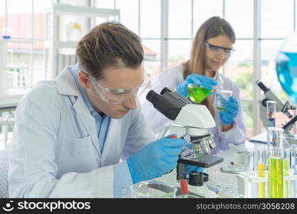 A western scientists couple working on test tube to analysis and develop vaccine of covid-19 virus in lab or laboratory in technology medical, chemistry, healthcare, research. Experimental science.