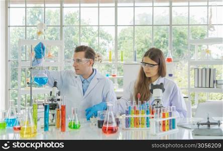 A western scientists couple working on test tube to analysis and develop vaccine of covid-19 virus in lab or laboratory in technology medical, chemistry, healthcare, research. Experimental science.