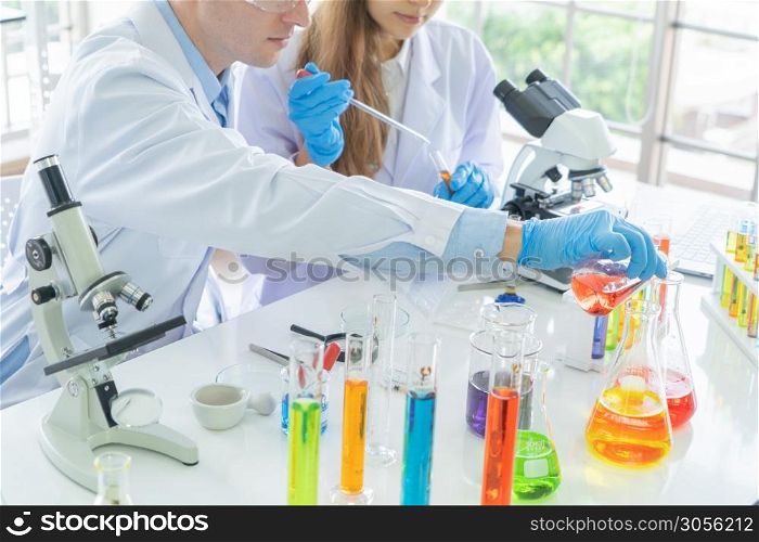 A western scientists couple working on test tube to analysis and develop vaccine of covid-19 virus in lab or laboratory in technology medical, chemistry, healthcare, research. Experimental science.