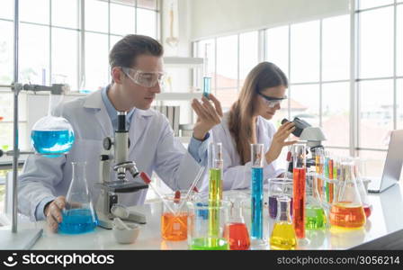 A western scientists couple working on test tube to analysis and develop vaccine of covid-19 virus in lab or laboratory in technology medical, chemistry, healthcare, research. Experimental science.