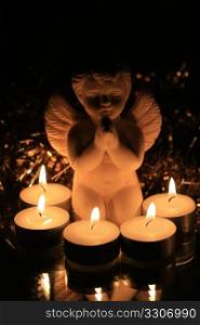 A white angel saying a prayer in candle light