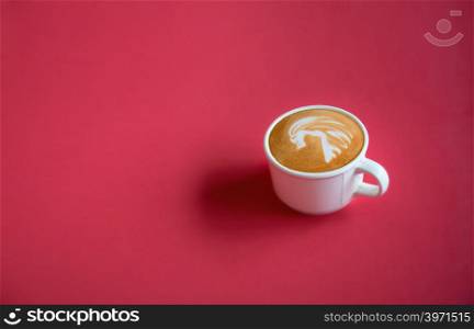 A white cup of hot coffee latte art on red background with copy space or space for text, design for wide banner, poster, postcard, Top view.