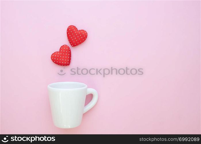 A white cup with polka dots red hearts on pink background. Copy space