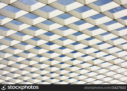 A white geometric ironwork lattice is an architectural abstract pattern when outlined against the sky.