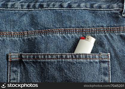 A white lighter in the back pocket of a denim jean pants