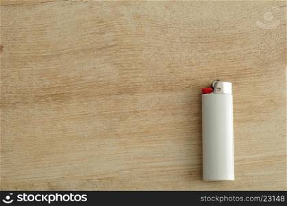 A white lighter isolated on a wooden background