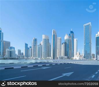 A white mosque near Dubai marina with road in downtown skyline, United Arab Emirates or UAE. Financial district and business area in smart urban city. Skyscraper and high-rise buildings at noon.