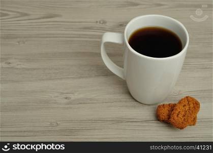 A white mug with coffee and golden square biscuits