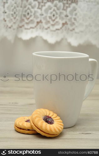 A white mug with coffee and round jam filled biscuits