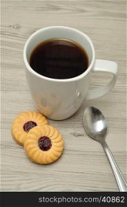 A white mug with coffee and round jam filled biscuits
