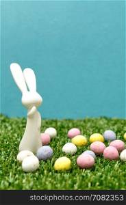 A white plastic bunny figurine displayed with speckled easter eggs