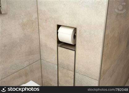 A white roll of soft toilet paper neatly hanging on a modern chrome holder in the wall close-up. A white roll of soft toilet paper neatly hanging on a modern chrome holder in the wall