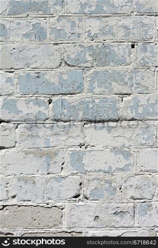 A white roughly textured brick wall painted with white paint