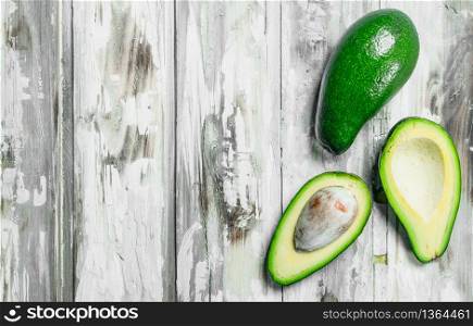 A whole avocado, and avocado slices. On a white wooden background.. A whole avocado, and avocado slices.