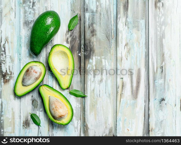 A whole avocado, and avocado slices. On a white wooden background.. A whole avocado, and avocado slices.