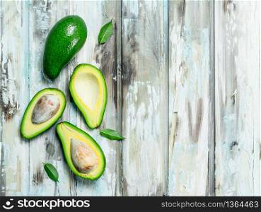 A whole avocado, and avocado slices. On a white wooden background.. A whole avocado, and avocado slices.