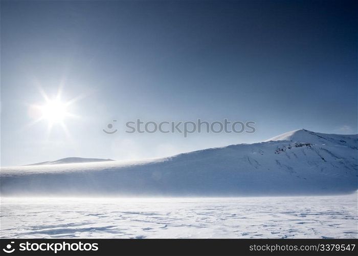 A wilderness winter mountain landscape looking into the sun