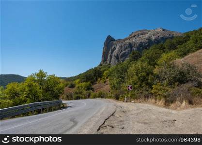 A winding asphalt road on the Black Sea coast of Crimea on a summer sunny day.