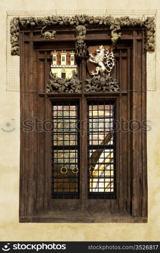 A window on the exterior of the City Hall building in Prague&rsquo;s Old Town main square. The castle and lion symbols represent Prague&rsquo;s history. The brighly painted interior is visible through the windowpanes.