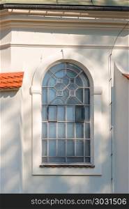 a window with an arch and a lattice, a white wall of a building