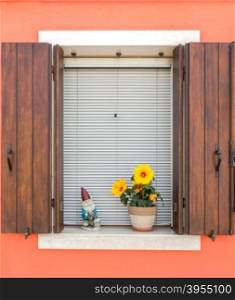 A window with shutters, blinds and a flower in a traditional house on Burano island. Venice.