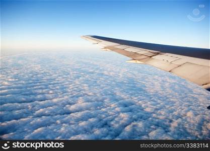 A wing of an airplane flying of a cloudscape
