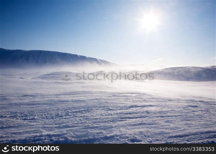 A winter landscape with a mountain and blue sky