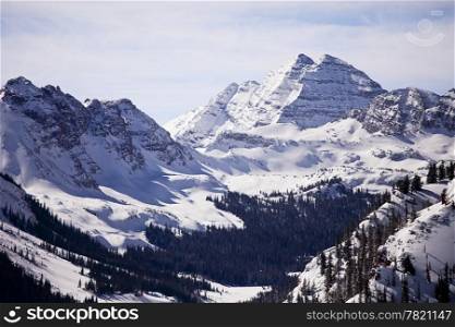 A winter view of the Maroon Bells mountain peaks in Colorado from a nearby mountain.