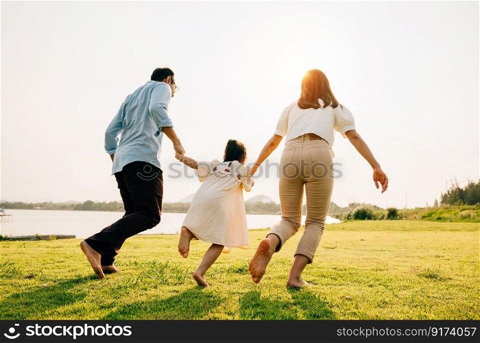 A woman and a man holding hands and running towards the sunset, with their child and dog in tow, on a carefree summer vacation, happy family