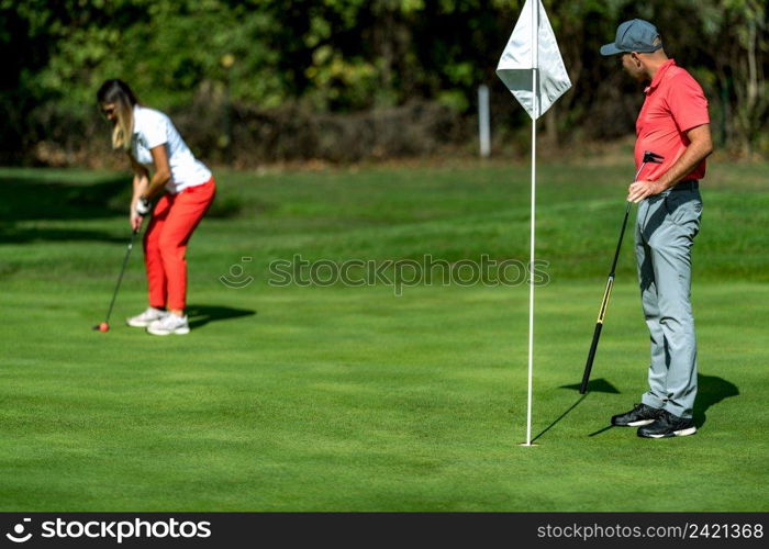 A woman and a man playing golf, woman putting