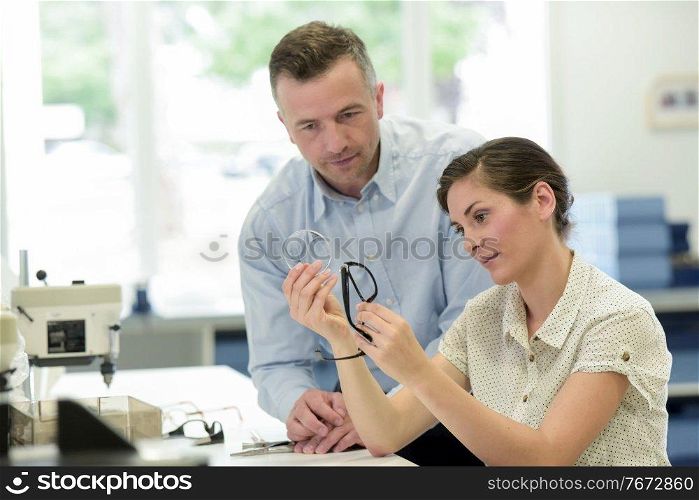 a woman and man fixing glasses in lab