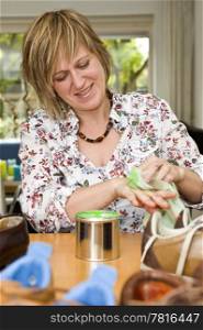 A woman cleaningher hands with a green liquid from a tin can after havng polished many pairs of shoes.