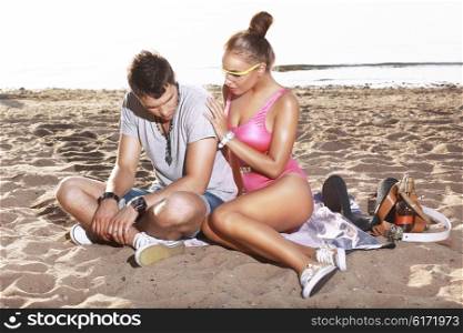 A woman comforts a man on the beach.