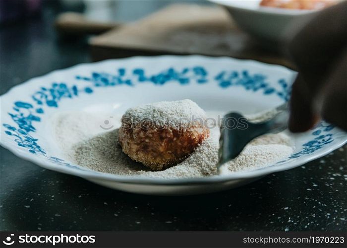 A woman cooking meatballs on the kitchen over a beauty old plate