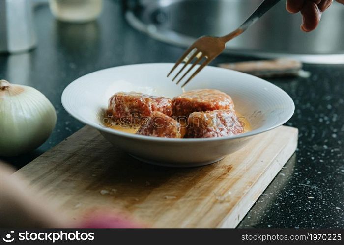 A woman cooking meatballs on the kitchen over a beauty old plate