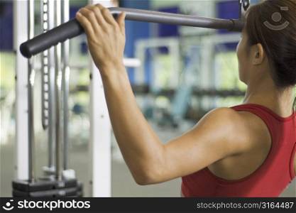 A woman demonstrates a lat pulldown exercise in a gym