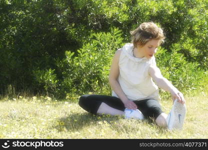 A woman doing stretching exercises in a park. woman, adult, alone, beauty, casual, female, blonde, fitness, exercise, yoga, stretching, location, time out, holiday, active, fit, lifestyle, good lo...