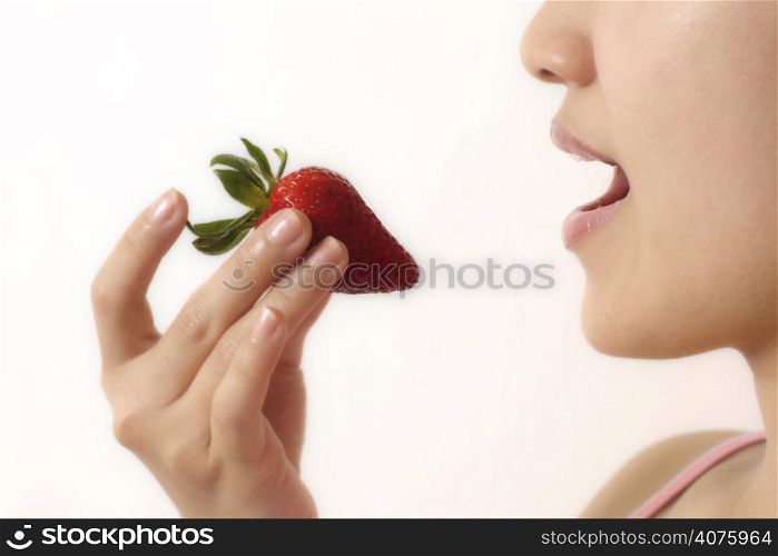 A woman eating a strawberry