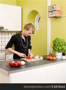 A woman feeling happy and cutting vegetables at home on the counter.