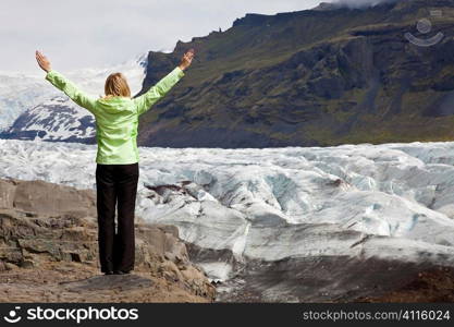 A woman hiker arms raised celebrating by the Vatnajokull Glacier, Iceland