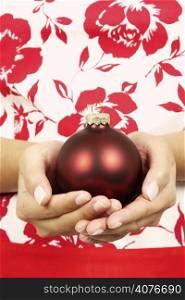 A woman holding a christmas ornament on her hand
