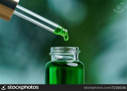 A woman holding a dropper with green hemp oil liquid. Laboratory concept.