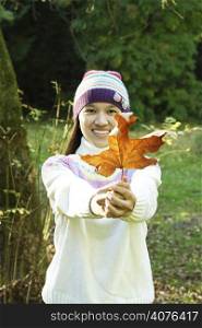 A woman holding an autumn or fall leaf