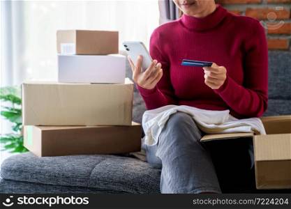 A woman holding phone and using credit card place an order shopping online