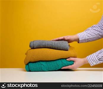 a woman holds a stack of washed folded things on a yellow background. Home routine work