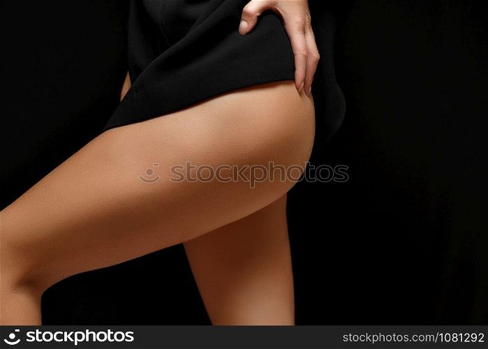 a woman in a black jacket on a naked body posing on a black background Baring her legs and hips