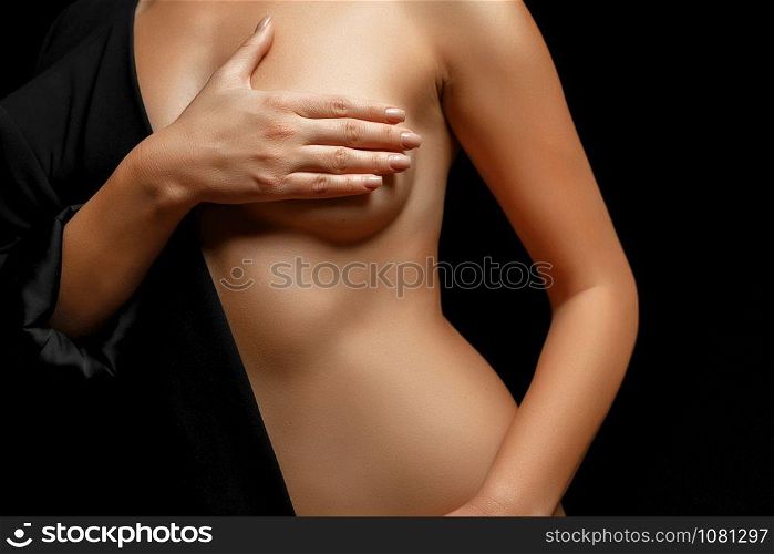 a woman in a black jacket on a naked body posing on a black background covering her Breasts