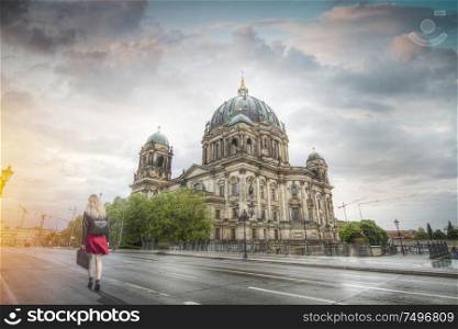 A woman in a red skirt walks along the avenue near the Berlin Cathedral. Germany