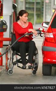 a woman in a wheelchair fills up her car at a gas station